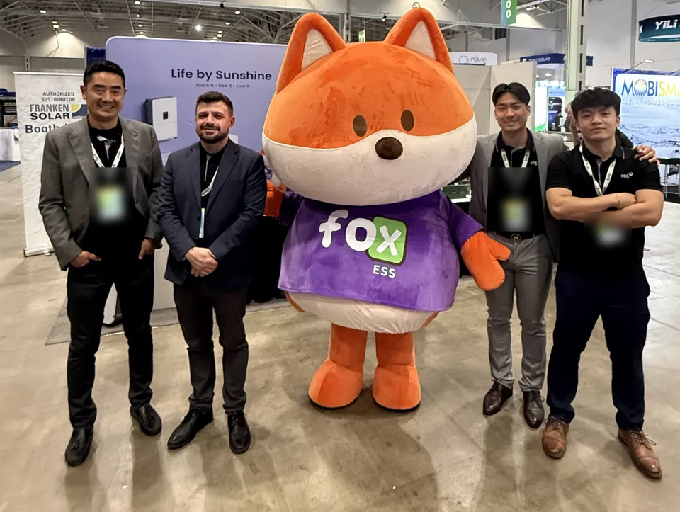 A posed group beside the Fox ESS mascot at an exhibition